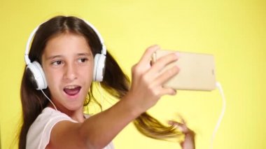 Genç kız mobil müzik renk arka plan üzerinde telefon ve kulaklık ile. yakın çekim, 4k, ağır çekim. selfi smartphone yapar