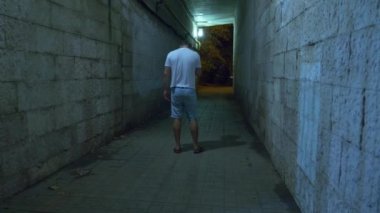 Sarhoş bir adam yalnız gece bir yaya tüneli üzerinden yürür. 4k.
