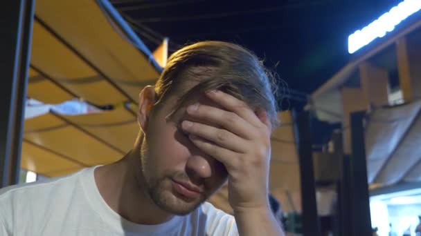 Eine traurige Person, die nachts in einem Fast-Food-Restaurant draußen sitzt. Allein. 4k — Stockvideo