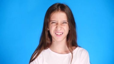 şirin kız Genç kamera gülüyor içine bakar ve komik bir yüz ifadesi yapar. 4 k, ağır çekim, yakın çekim. renk arka plan