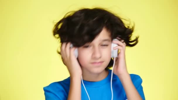 Tonåring pojke med hörlurar och mobiltelefon Lyssna på musik på färgbakgrund. närbild, 4k, slow motion. — Stockvideo