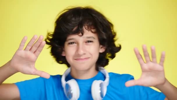 Niño adolescente con auriculares y teléfono móvil escuchando música en el fondo de color. primer plano, 4k, cámara lenta . — Vídeos de Stock