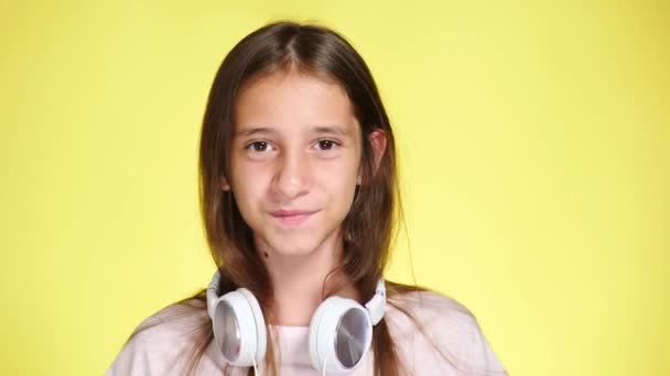 Teenage girl with headphones listening to music on color background. close-up, 4k, slow-motion. — Stock Video