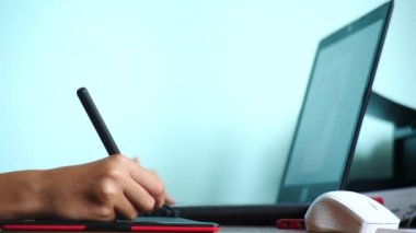 yakın çekim. Kız bir grafik tablet üzerinde çizin. Serbest. Bir el ile bir kırmızı siyah tablet üzerinde hareketli bir pikap iğnesi. 4k, ağır çekim. renk arka plan. kopya alanı