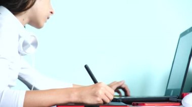 yakın çekim. Kız bir grafik tablet üzerinde çizin. Serbest. Bir el ile bir kırmızı siyah tablet üzerinde hareketli bir pikap iğnesi. 4k, ağır çekim. renk arka plan. kopya alanı