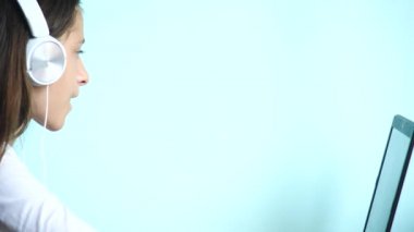 yakın çekim arka plan. Renkli bir arka planda beyaz kulaklık güzel bir genç kızı dizüstü bilgisayar ekranında görünüyor. ağır çekim, 4k