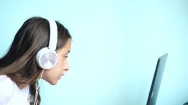 yakın çekim arka plan. Renkli bir arka planda beyaz kulaklık güzel bir genç kızı dizüstü bilgisayar ekranında görünüyor. ağır çekim, 4k