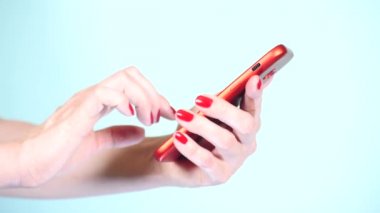 yakın çekim, eller kırmızı manikür ile renkli bir arka plan üzerine bir akıllı telefon kullanın. 4k, ağır çekim çekim