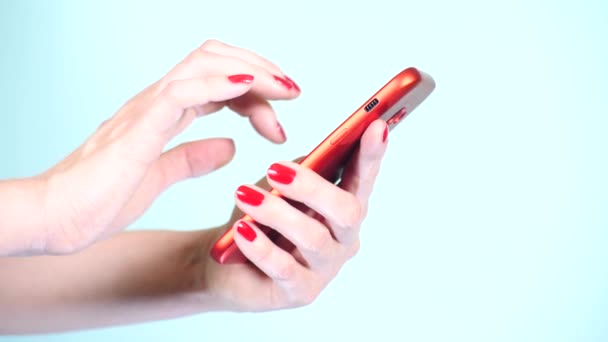クローズ アップ、赤のマニキュアと女性の手は、色付きの背景にスマート フォンを使用します。4 k、スローモーション撮影 — ストック動画
