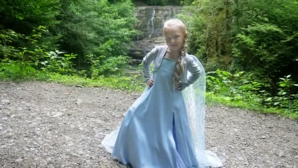 Modelo niña en un hermoso vestido azul posando contra una cascada en el bosque. 4k, cámara lenta . — Vídeos de Stock