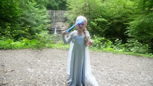Kleines Mädchen Modell in einem schönen blauen Kleid posiert vor einem Wasserfall im Wald. 4k, Zeitlupe. — Stockvideo