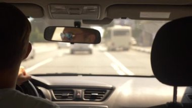 Güneş gözlüklü genç yakışıklı bir adam bir araba şehir etrafında sürüş. dikiz aynası yansıması. 4k, ağır çekim