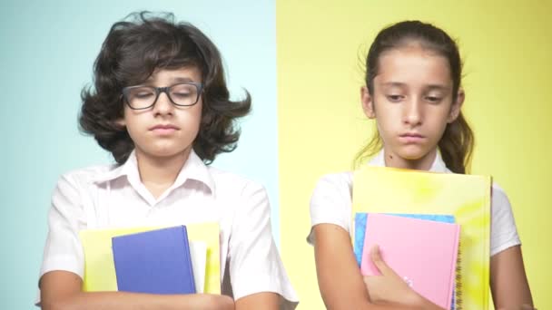 Retratos de crianças em uniforme escolar em um fundo colorido. Crianças engraçadas. Irmã e irmão. conceito de aprendizagem. Estão tristes porque não querem ir à escola. espaço de cópia — Vídeo de Stock