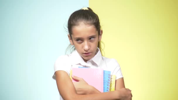 Portretten van een tiener in school uniform op een gekleurde achtergrond. concept van leren. De tiener maakt grappige gezichten. ze wanhopig omdat hij niet wil om naar school te gaan. kopie ruimte — Stockvideo