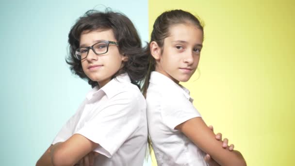 Retratos de niños en uniforme escolar sobre un fondo de color. Niños graciosos. Hermana y hermano. concepto de escolaridad. Miran a la cámara y muestran el pulgar hacia arriba. espacio de copia — Vídeo de stock