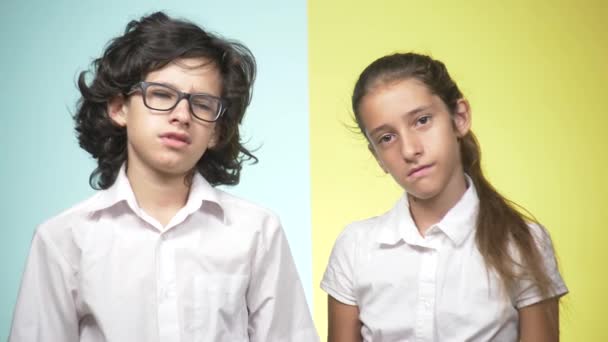 Retratos de niños en uniforme escolar sobre un fondo de color. Niños graciosos. Hermana y hermano. concepto de aprendizaje. Están tristes porque no quieren ir a la escuela. espacio de copia — Vídeos de Stock