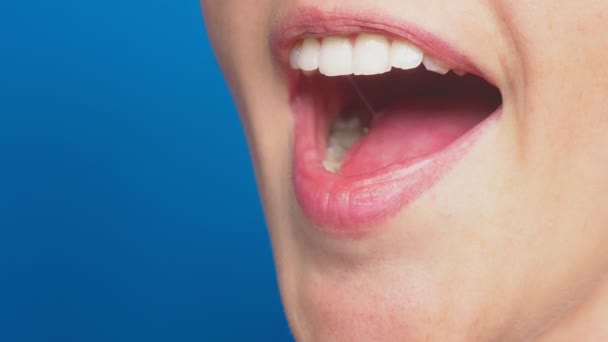 Primer plano, labios femeninos sin maquillaje, sobre un fondo azul. 4k, disparos en cámara lenta. la emoción de la sorpresa . — Vídeos de Stock