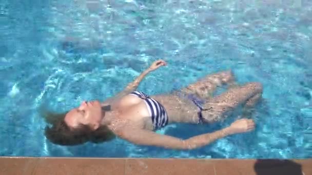 Νεαρή όμορφη γυναίκα ξαπλωμένη σε ένα κοστούμι λουσίματος ξαπλωμένος στο νερό σε εξωτερικούς χώρους. 4k, αργή κίνηση — Αρχείο Βίντεο