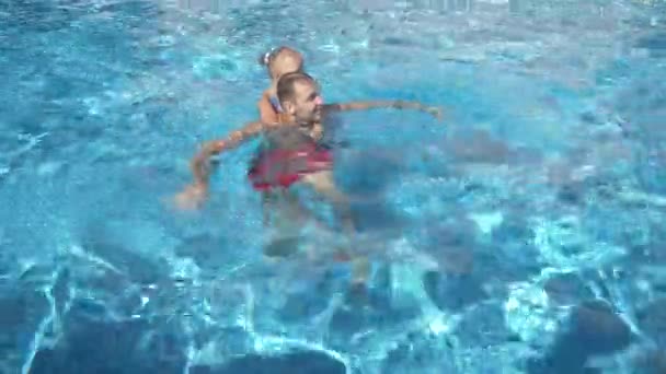 Młody ojciec uczy jego córeczka, aby popływać w basenie. Szczęśliwa dziewczyna i jej ojciec śmiać się i bawić. 4 k. zwolnionym tempie — Wideo stockowe