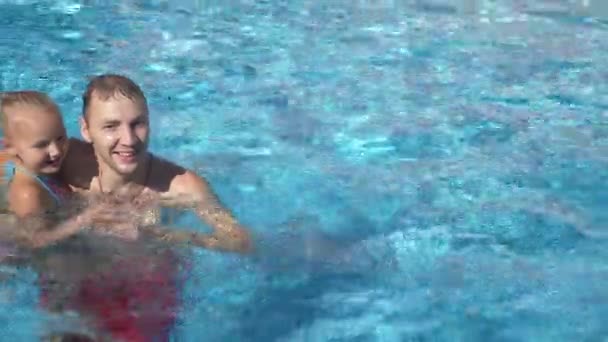 El joven padre le está enseñando a su hija a nadar en la piscina. La chica feliz y su padre se ríen y se divierten. 4k. Movimiento lento — Vídeo de stock