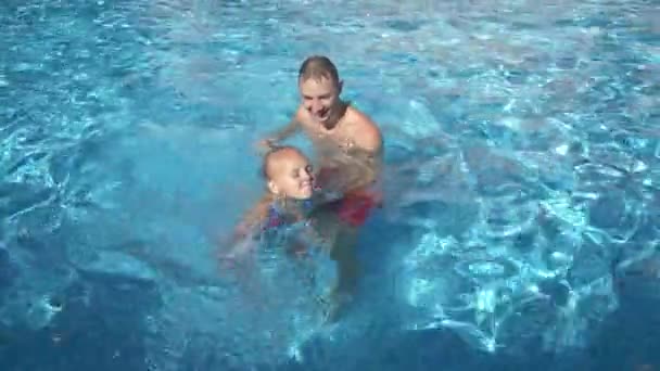 O jovem pai está a ensinar a filha a nadar na piscina. A menina feliz e seu pai rir e se divertir. 4K. Movimento lento — Vídeo de Stock