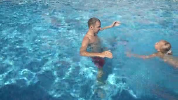 Ο νεαρός πατέρας διδασκαλία μικρή του κόρη να κολυμπήσουν στην πισίνα. Ο ευτυχισμένος κορίτσι και ο πατέρας της γελούν και να διασκεδάσετε. 4 k. αργή κίνηση — Αρχείο Βίντεο