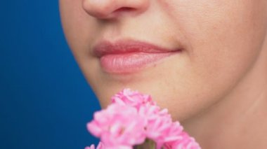 yakın çekim, kadın dudak makyaj olmadan kız gül burnunu çekmek. mavi bir arka plan üzerinde. 4k, ağır çekim