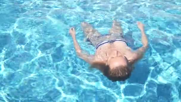 Молодая красивая лежащая женщина в купальнике, лежащем в воде на открытом воздухе. 4k, slow motion — стоковое видео