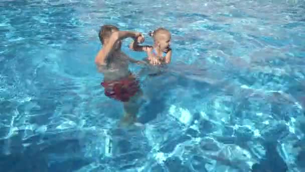 Der junge Vater bringt seiner kleinen Tochter das Schwimmen im Pool bei. das glückliche Mädchen und ihr Vater lachen und haben Spaß. 4k. Zeitlupe — Stockvideo