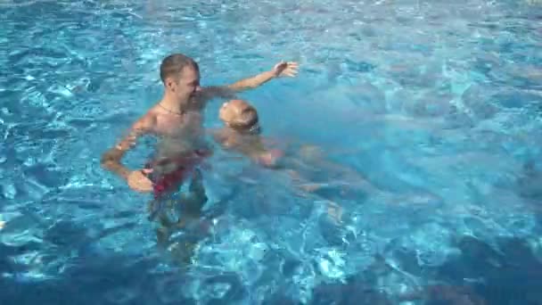 Ο νεαρός πατέρας διδασκαλία μικρή του κόρη να κολυμπήσουν στην πισίνα. Ο ευτυχισμένος κορίτσι και ο πατέρας της γελούν και να διασκεδάσετε. 4 k. αργή κίνηση — Αρχείο Βίντεο