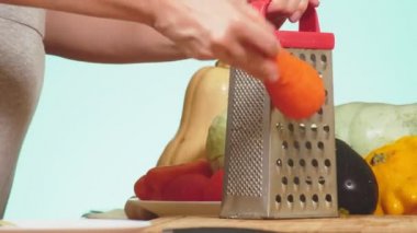 rendelenmiş havuç ovuşturdu eller. Sebze Güveç yemek pişirmek için sebze karışımı. arka plan rengi. 4k, sağlıklı beslenme ve hasat kavramı.