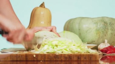 lahana bir bıçak ile kesmek eller. Sebze Güveç yemek pişirmek için sebze karışımı. arka plan rengi. 4k, sağlıklı beslenme ve hasat kavramı.