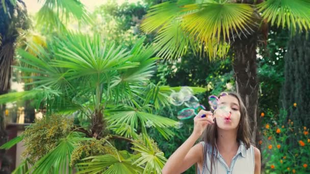 여자 십 대 갈색 머리 열 대 공원 배경 비누 거품을 불고. 4 k, 슬로우 모션 — 비디오