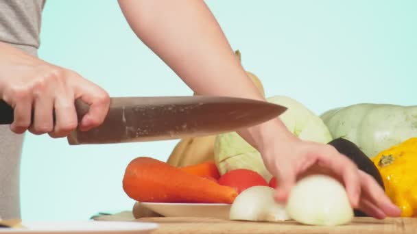 Una mano femenina se corta con un cuchillo una cebolla. mezcla de verduras para cocinar estofado de verduras. color de fondo. 4k, el concepto de alimentación saludable y cosecha . — Vídeos de Stock