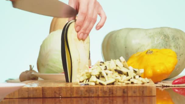 Le mani femminili tagliano una melanzana con un coltello. miscela di verdure per la cottura di stufato di verdure. colore di sfondo. 4k, il concetto di sana alimentazione e raccolta . — Video Stock