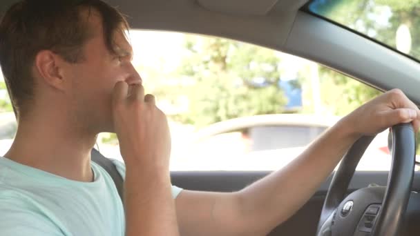 El hombre al volante del coche, come comida rápida, mientras el coche se mueve. en un día soleado de verano. 4k, cámara lenta — Vídeo de stock