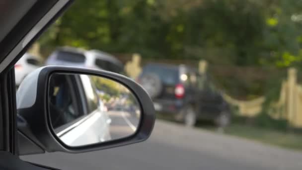 Kijk uit de achteruitkijkspiegel, wanneer de auto langs de weg in de zomer passeert. 4k, slow-motion-video schieten — Stockvideo