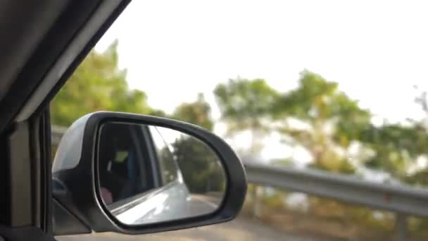 Kijk uit de achteruitkijkspiegel, wanneer de auto langs de weg in de zomer passeert. 4k, slow-motion-video schieten — Stockvideo