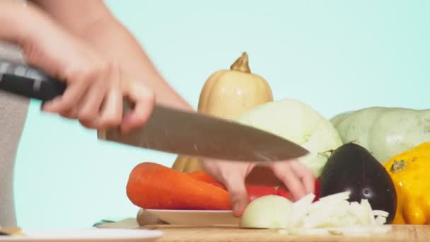 Egy női kéz egy késsel vágják egy hagyma. zöldségek, zöldség pörkölt főző keveréke. háttérszín. 4k, az egészséges táplálkozás és betakarítás. — Stock videók