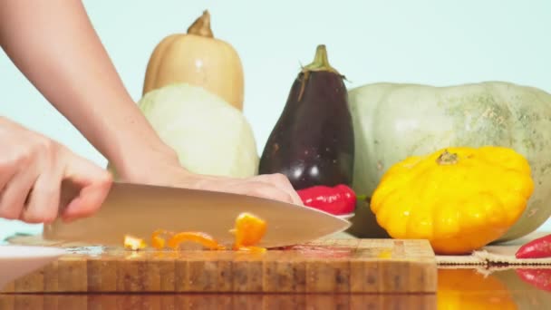 Las manos femeninas se cortan con un cuchillo naranja pimiento. mezcla de verduras para cocinar estofado de verduras. color de fondo. 4k, el concepto de alimentación saludable y cosecha . — Vídeo de stock