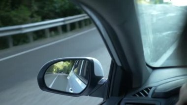 Arabayı yolda yaz aylarında geçerken dikiz aynası görüntüleyin. 4k, ağır çekim çekim