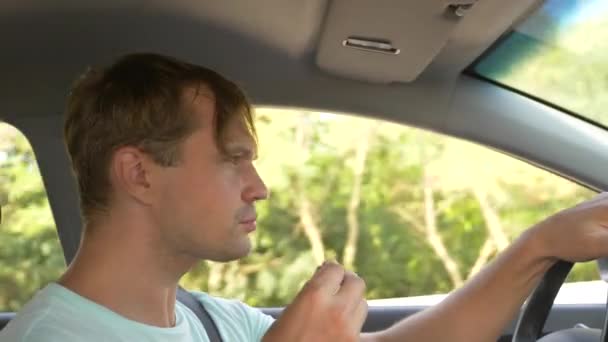 Muž za volantem auta, jí rychlého občerstvení, zatímco auto je v pohybu. v letní slunečný den. 4k, pomalý pohyb — Stock video