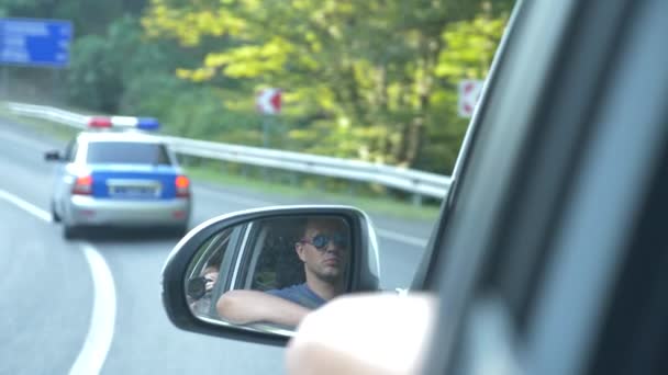Vista al espejo retrovisor, cuando el coche pasa a lo largo de la carretera en el verano. 4k, disparo en cámara lenta — Vídeo de stock