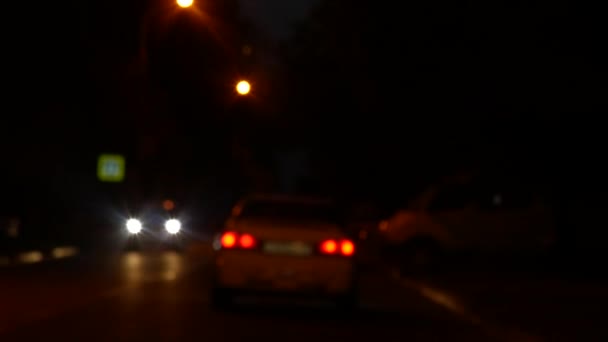 Conduzir à noite. Veja o pára-brisas e carros embaçados na cidade. janela do carro dianteiro com um tráfego turvo da cidade nas ruas da cidade. 4k — Vídeo de Stock