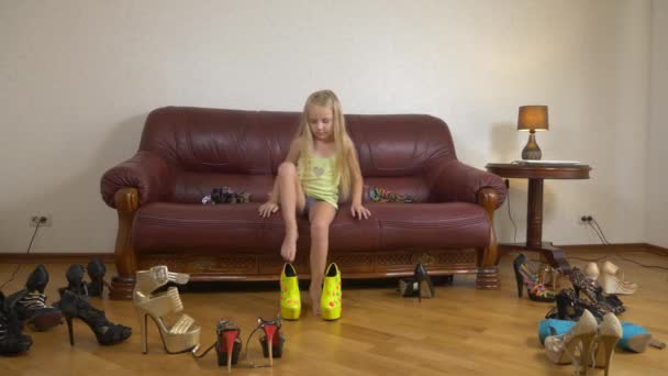 Una niña está jugando con zapatos de tacón alto. Las piernas de un niño pequeño en zapatos para adultos. chica con tacones altos. 4k — Vídeos de Stock