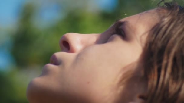 Närbild. flicka Tonåring tittar upp på himlen utomhus. ansikte i profil. 4k. — Stockvideo