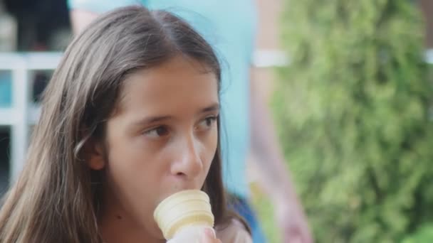 Adolescente menina comendo sorvete em um cone, ao ar livre. 4k, close-up . — Vídeo de Stock