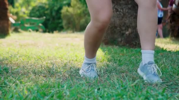Gros plan des pieds dansants. Une adolescente danse dans le parc sur un fond d'herbe verte. 4k, gros plan — Video