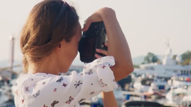 Girl photographer takes pictures of a model on a sea dock on the background of yachts. 4k. — Stock Video