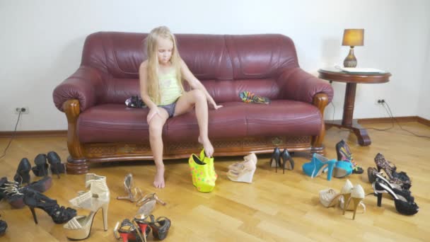 Une petite fille joue avec des chaussures à talons hauts. Les jambes d'un petit enfant en chaussures pour adultes. fille en talons hauts. 4k — Video